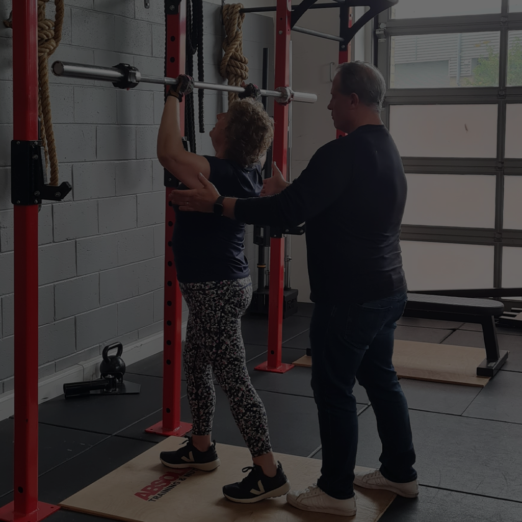 a personal trainer showing a client how to use a weighted bar