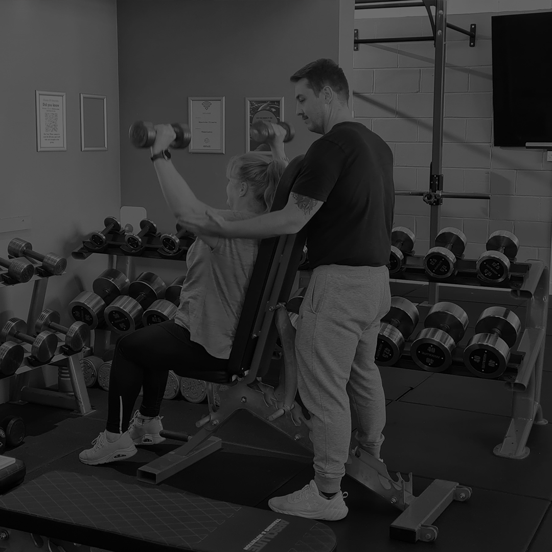 a personal trainer doing a one to one personal training session with a client showing them how to use dumbells