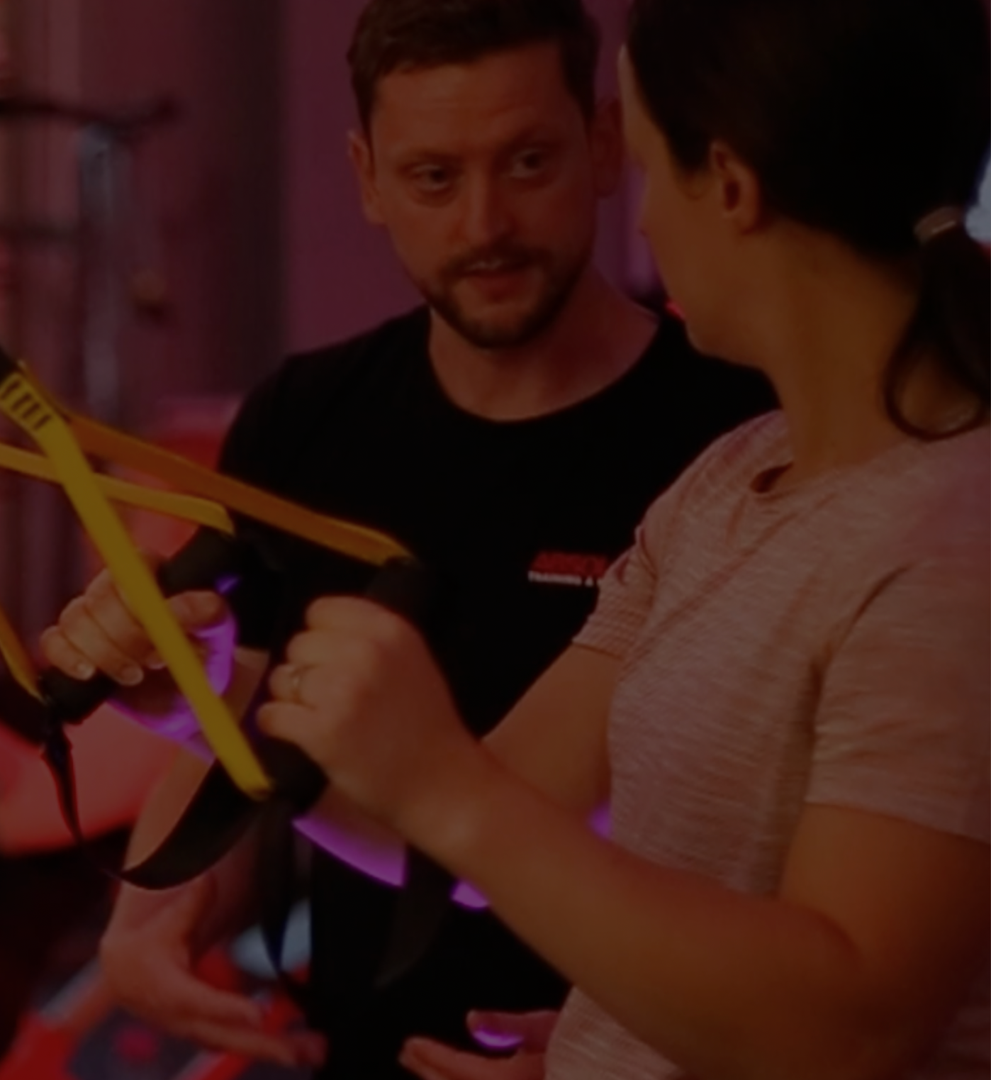 a picture of a personal trainer looking at a client whilst they are using the trx machine
